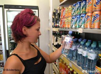 Eine Frau nimmt Plastikflaschen aus einem Regal Foto: