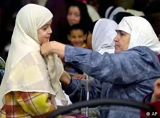 A Muslim woman adjusts the veil of a young girl in France.