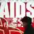 Plakat s natpisom AIDS, jedna žena prolazi pokraj plakata