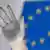 Mano derecha abierta de una estatua frente a la bandera de la UE