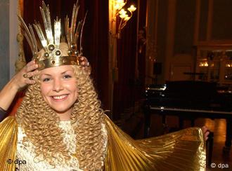 Eine junge Frau mit einer blonden Perücke, einer goldenen Krone und einem langen Kleid mit goldenem Umhang