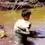 Ein kleiner Junge wäscht an einem Fluss in Laos Zinn aus (Archiv), Foto: dpa