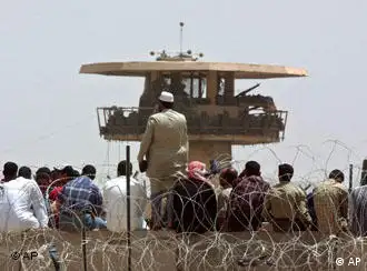 Iraqis wait outside the prison where the torturing took place