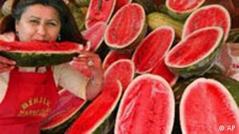 Eine Melonenverkäuferin erfrischt sich mit einem Stück Wassermelone