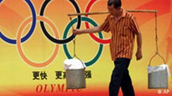 Ein Wasserträger vor einem Olympia-Plakat in Peking (24.8.2004)