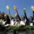 Five women holding up big beer glasses into the deep blue sky