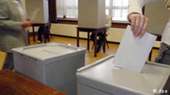 Eine Hand steckt einen Zettel in eine Wahlurne (Foto: dpa)