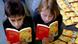 Zwei Kinder liegen auf dem Boden und lesen Zwei Kinder liegen auf dem Boden und lesen