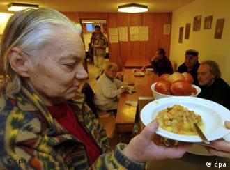 Ältere Frau nimmt eine Telle Suppe in einer Suppenküche für Obdachlose (Foto: dpa)