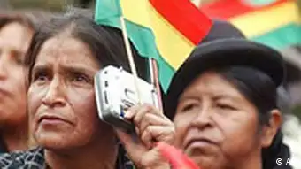 An Andean woman listens to the news using a small radio 