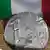 Defekte Euro Münze mit der Italienischen Flagge im Hintergrund --- DW-Grafik: Peter Steinmetz