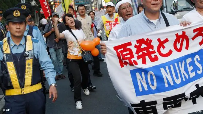 Demonstrators walk by the headquarters of Tokyo Electric Power Co., operator of tsunami-hit Fukushima Daiichi nuclear plant