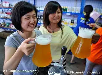 Two Chinese women hold up mugs of beer at a German-style beer festival in downtown Qingdao city, eastern China's Shandong province, 09 July 2010. The festival runs from 09 to 25 July, providing over 30 kinds of German beer products with more than 16 kinds of German-style snack foods to people. EPA/WU HONG +++(c) dpa - Bildfunk+++