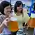 Two Chinese women hold up mugs of beer at a German-style beer festival in downtown Qingdao city, eastern China's Shandong province, 09 July 2010. The festival runs from 09 to 25 July, providing over 30 kinds of German beer products with more than 16 kinds of German-style snack foods to people. EPA/WU HONG +++(c) dpa - Bildfunk+++