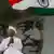 India's most prominent anti-corruption crusader Anna Hazare applauds as he sits in the backdrop of a portrait of Mahatma Gandhi