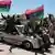 Libysche Rebellen sitzen auf einem Auto und schwenken Fahnen und strecken ihre Arme siegessicher in die Höhe (Archivfoto: pa/dpa)