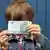 Junge mit Geldschein vor dem Gesicht (Foto: Fotolia)