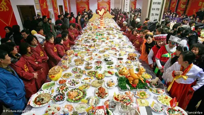 People look at dishes displayed on a large table during a dishes show event for the upcoming Chinese lunar New Year's Eve dinner in downtown Wuhan city, central China's Hubei province, 07 February 2010. More than 15,000 dishes were made by 9,048 families to celebrate the upcoming Chinese lunar New Year, also called Spring Festival which falls on 14 February, the first day of the 'Year of Tiger'. EPA/STR