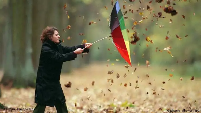 Eine Frau hält ihren Regenschirm fest, der vom Wind umgebogen wurde (picture alliance /dpa)