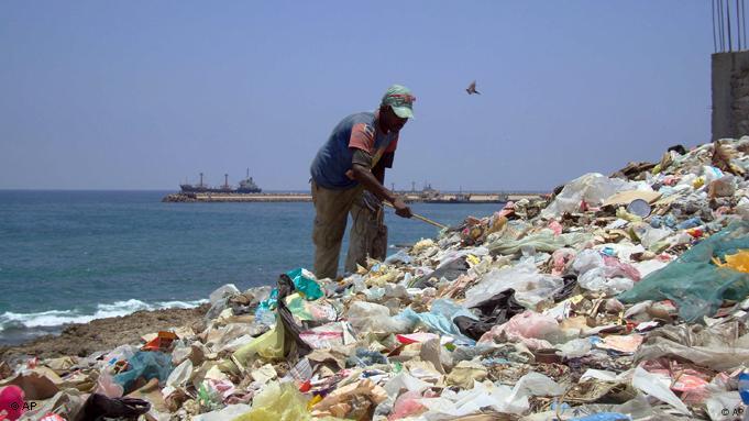 A Somali man sifting through a mountain of trash