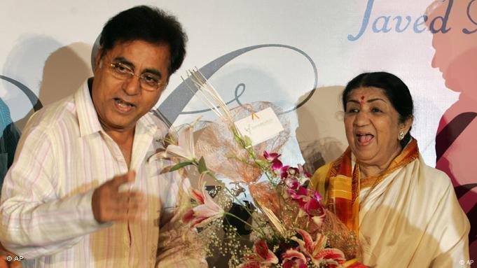 Singer Jagjit Singh speaks next to Lata Mangeshkar who is laughing, in her hands she holds a bouquet of flowers Singer Jagjit Singh speaks next to Lata Mangeshkar who is laughing, in her hands she holds a bouquet of flowers