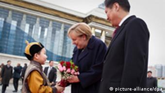 Angela Merkel (M.) nimmt Blumen von einem kleinen Jungen (l.) in Ulan Bator in der Mongolei bei der begrüßung mit Ministerpräsident Sukhbaatar Batbold entgegen(Foto: dpa )