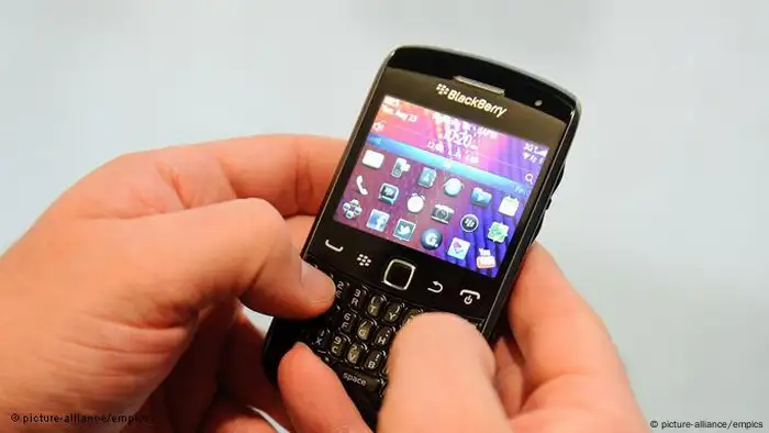 Zwei Hände tippen auf der Tastatur eines BlackBerry-Handys.