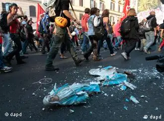 Demonstrators walk past a broken statue of the Virgin Mary as clashes broke out between protesters and police in Rome, Saturday, Oct. 15, 2011. Protesters smashed the windows of shops in Rome and torched a car as violence broke out during a demonstration in the Italian capital, part of worlwide protests against corporate greed and austerity measures. (Foto:Gregorio Borgia/AP/dapd)