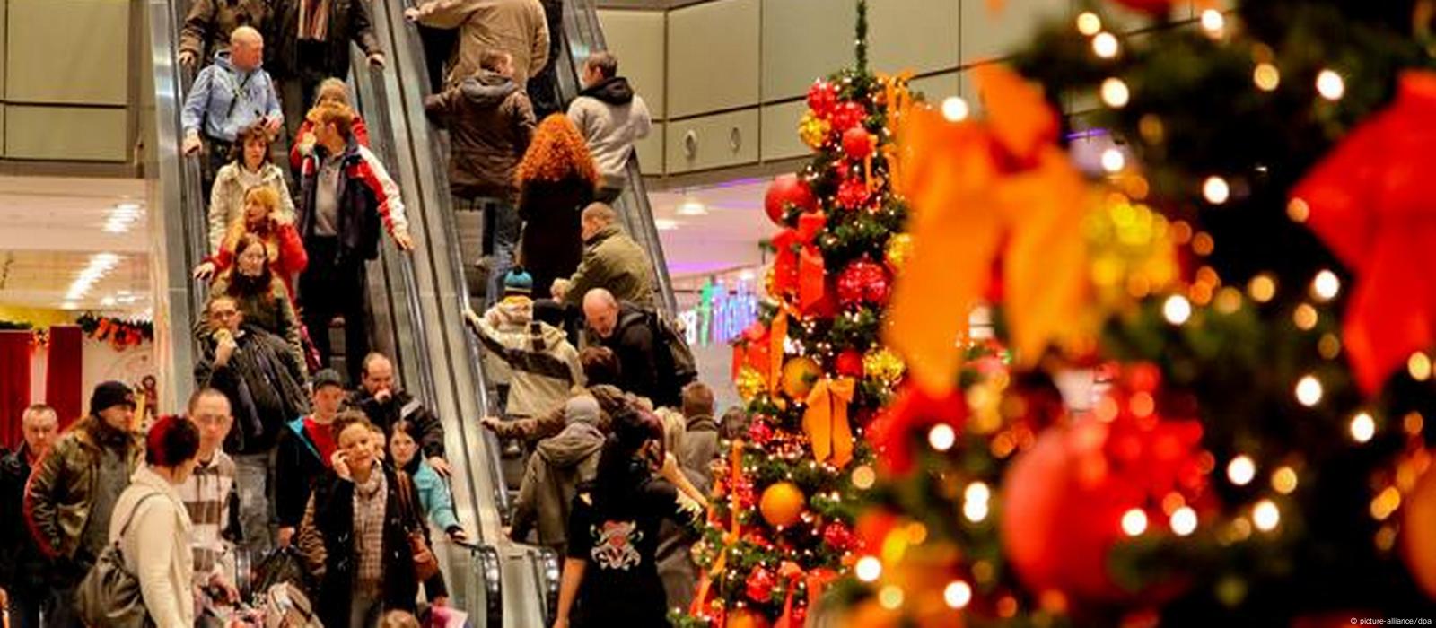 Blick in ein weihnachtlich geschmÃ¼cktes Einkaufszentrum mit vollen Rolltreppen.