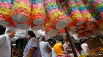 Residents walk past floats made for the Loy Krathong festival at a flower market in Bangkok, Thailand, Wednesday, Nov. 9, 2011. Every year when the moon is full and the rainy season draws to an end, millions of Thais fill their country's waterways with miniature lotus-shaped boats, setting them adrift with flickering candles in a centuries-old homage to a water goddess. This year, flood-ravaged Thailand has plenty of reason to pray for rebirth, and little reason to celebrate. (AP Photo/Aaron Favila)