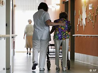 Një punonjëse e shërbimit të kujdesit po ndihmon një banore në një azil pleqsh.