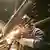 Sparks fly in the dark as a man welds metal sections in the metro train station under Hamburg's airport