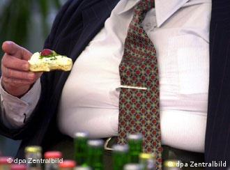 An overweight man eats an open sandwich