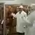 Zwei weiß gekleidete Inspekteure kontrollieren Schweinehälften (Foto: dw-tv)