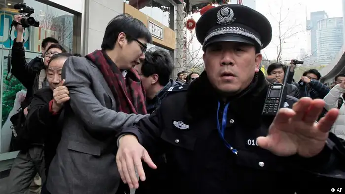 A man, 3rd from left, is detained by police officers in front of a cinema that was a planned protest site in Shanghai, China, Sunday, Feb. 20, 2011. Jittery Chinese authorities staged a show of force Sunday to squelch a mysterious online call for a Jasmine Revolution apparently modeled after pro-democracy demonstrations sweeping the Middle East. (AP Photo/Eugene Hoshiko)