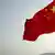 A Chinese flag flutters in the wind as an oil tanker is anchored offshore in the distance April 15, 2006 near Zhoushan, China (AP Photo/Eugene Hoshiko)