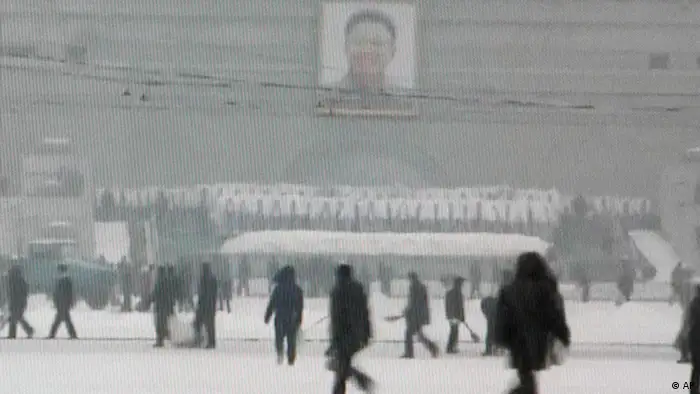 In this image made from CCTV television, North Koreans wipe the snow away in front of a huge portrait of late North Korean leader Kim Jong Il, in Pyongyang, North Korea, before his funeral, Wednesday, Dec. 28, 2011. (AP Photo/CCTV via APTN) TV OUT, CHINA OUT