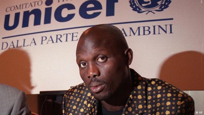 George Weah in front of a sign with the logo of the UN children fund UNICEF