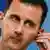 Syrian President Bashar Assad adjusts his earpiece during a news conference