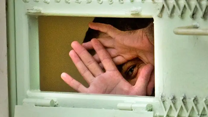 **FILE** In this Nov. 18, 2008 file photo, reviewed by the U.S. Military, a Guantanamo detainee peers through his hands from inside his cell at the Camp Echo detention facility at the U.S. Naval Base, in Guantanamo Bay, Cuba. A U.S. appeals court has overturned a ruling, Wednesday, Feb. 18, 2009, that would have transferred 17 Guantanamo Bay detainees to the United States. The men have been cleared for release from Guantanamo, but the United States will not send them home to China for fear they will be tortured. So they remain in prison while the U.S. figures out what to do with them. (ddp images/AP Photo/Brennan Linsley, File)