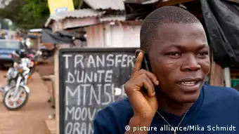 Ein afrikanischer Mann aus der Elfenbeinkueste telefoniert mit seinem Mobiltelefon.