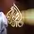 A Qatari employee of Al Jazeera Arabic language TV news channel passes by the logo of Al Jazeera in Doha