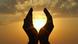 Hands cupping setting sun on horizon Hands cupping setting sun on horizon