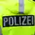 Полицейский стоит спиной в куртке с надписью "полиция"