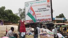 People sell their wares at a roadside market in Niamey, Niger, Thursday, Sept, 8. 2011 under a billboard advertising an Africa Cup of Nations soccer qualifier between Niger and South Africa. Niger's government said Wednesday it is welcoming on humanitarian grounds a group of 13 Libyans who arrived in a convoy but confirmed that ousted strongman Moammar Gadhafi is not among them. It said it was acting in consultation with the Libyan rebel National Transitional Council. The Libyans must refrain from taking any action or attitudes not compatible with those humanitarian conditions, said a statement released Wednesday after a Cabinet meeting headed by President Mahamadou Issoufou. (Foto:Sunday Alamba/AP/dapd)