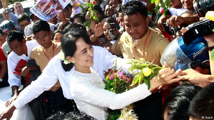 Myanmar's democracy icon Aung San Suu Kyi, center, receives flowers from supporters as she leaves the Yangon District Election Commission after submitting a candidates' list of her National League for Democracy for the upcoming parliamentary by-election on Wednesday, Jan.18, 2012, in Yangon, Myanmar. Suu Kyi registered to run for a seat representing Kawhmu, a poor district south of Yangon where villagers' livelihoods were devastated by Cyclone Nargis in 2008. (AP Photo/Khin Maung Win)