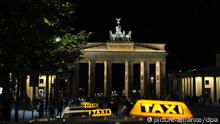 Ein Taxi bei Nacht vor dem beleuchteten Brandenburger Tor
