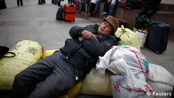 A migrant worker sleeps as he waits for his train outside Shanghai's railway station, January 19, 2012. Chinese New Year, or Spring Festival, is the biggest of two Golden Week holidays, giving migrant workers their only chance of the year to return to their home provinces with gifts for their families. More than 200 million people are expected to take to the railways over this year's holiday, the biggest movement of humanity in the world. REUTERS/Carlos Barria (CHINA - Tags: SOCIETY TRANSPORT)