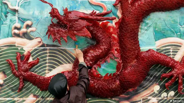A worker paints the background of a wall, installed with nine sugar dragons, during preparation work for the upcoming Lunar New Year at a park in Chengdu, Sichuan province January 17, 2012. The Lunar New Year, or Spring Festival, begins on January 23 and marks the start of the Year of the Dragon, according to the Chinese zodiac. REUTERS/Stringer (CHINA - Tags: ANNIVERSARY SOCIETY) CHINA OUT. NO COMMERCIAL OR EDITORIAL SALES IN CHINA