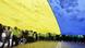 Люди несут огромный флаг Украины Люди несут огромный флаг Украины